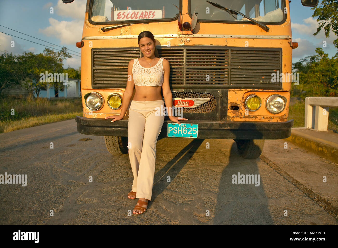 Smiling girl posing in front of an old school bus in the Valle de Viñales in central Cuba Stock Photo