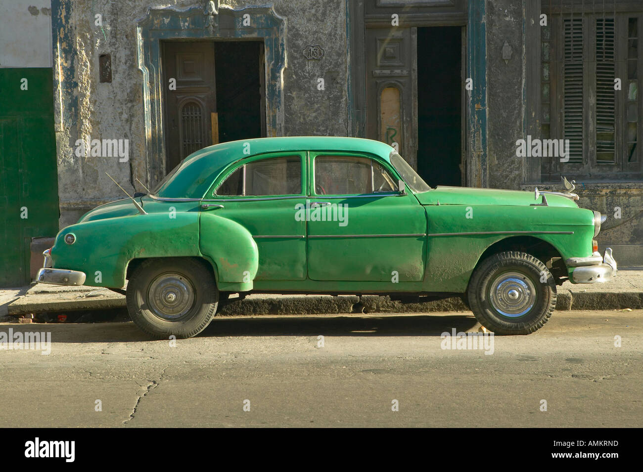 An old green car sitting in front of old building in Old Havana Cuba Stock Photo
