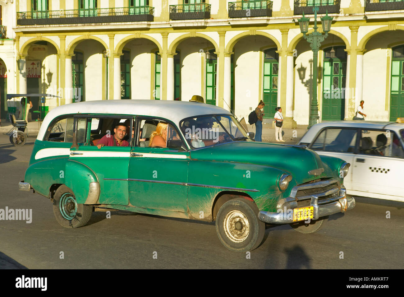 An old American green car and taxi driving through Old Havana Cuba Stock Photo