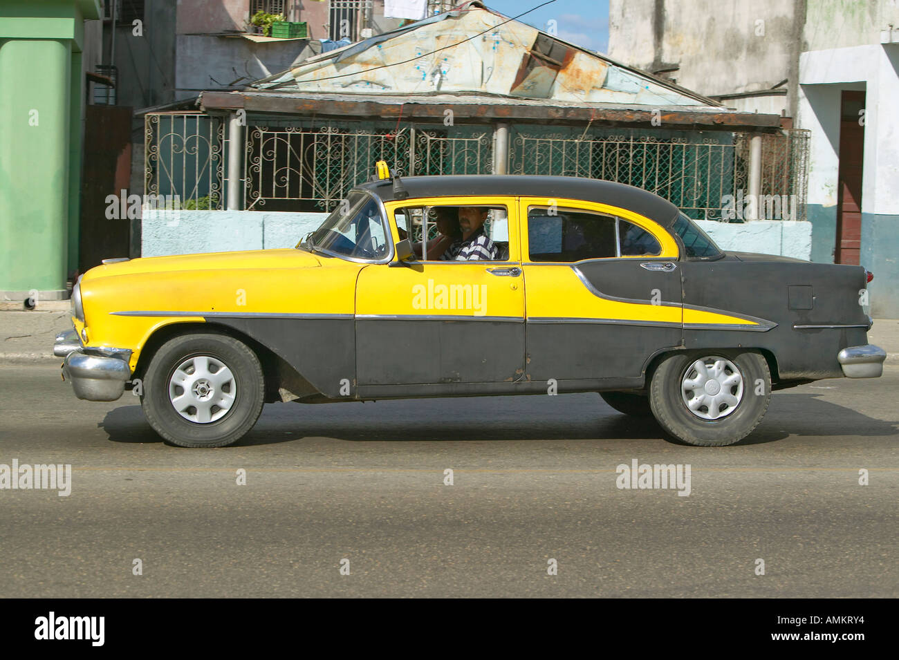 1955 yellow Oldsmobile driving through the streets of Havana Cuba Stock Photo