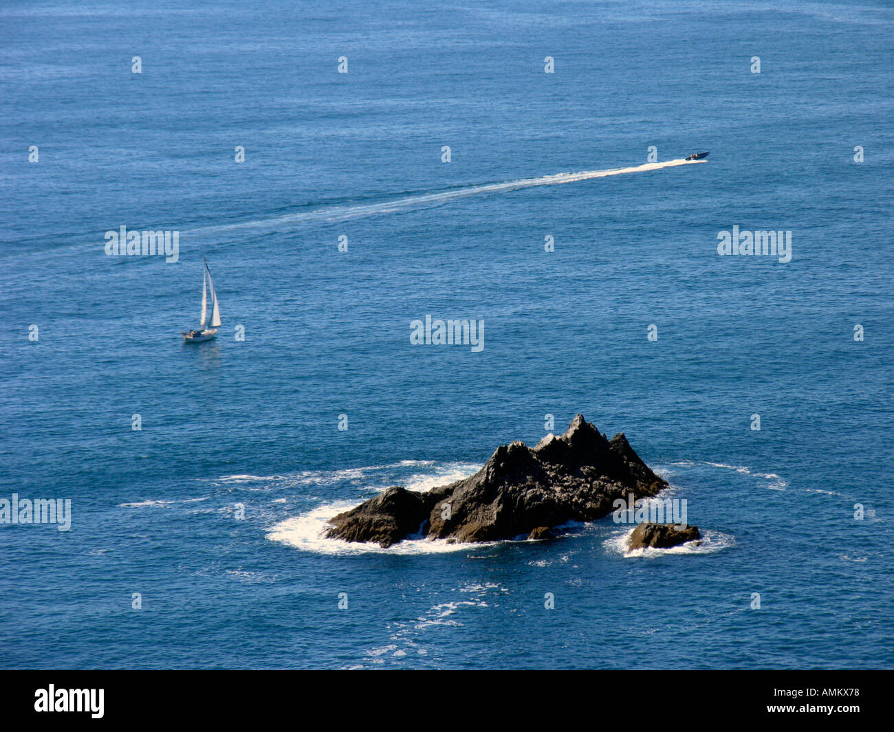 A yacht and motorboat sailing in a blue summer sea off the South Devon coast. UK Stock Photo