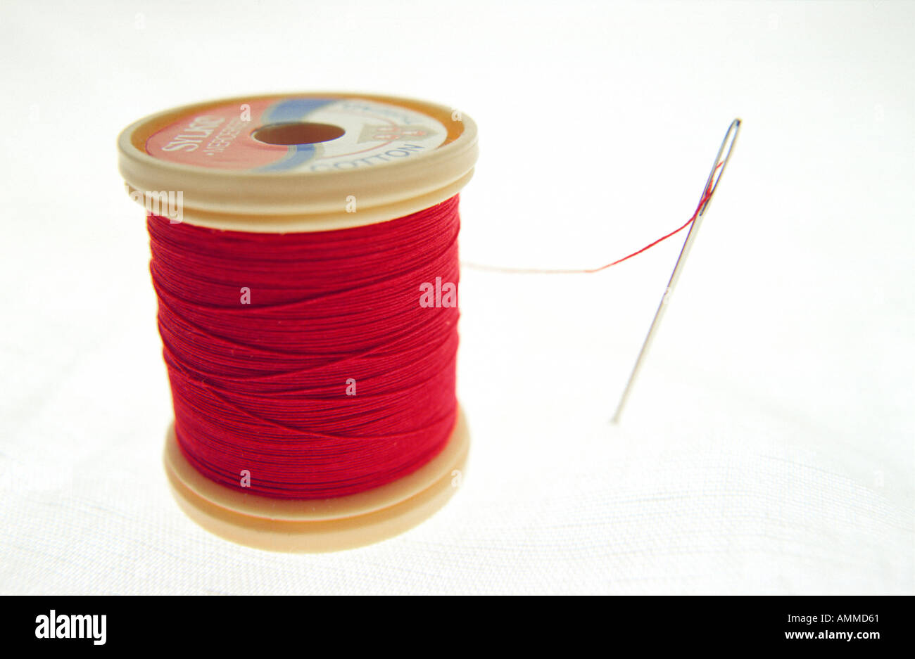 Red cotton reel and needle Stock Photo