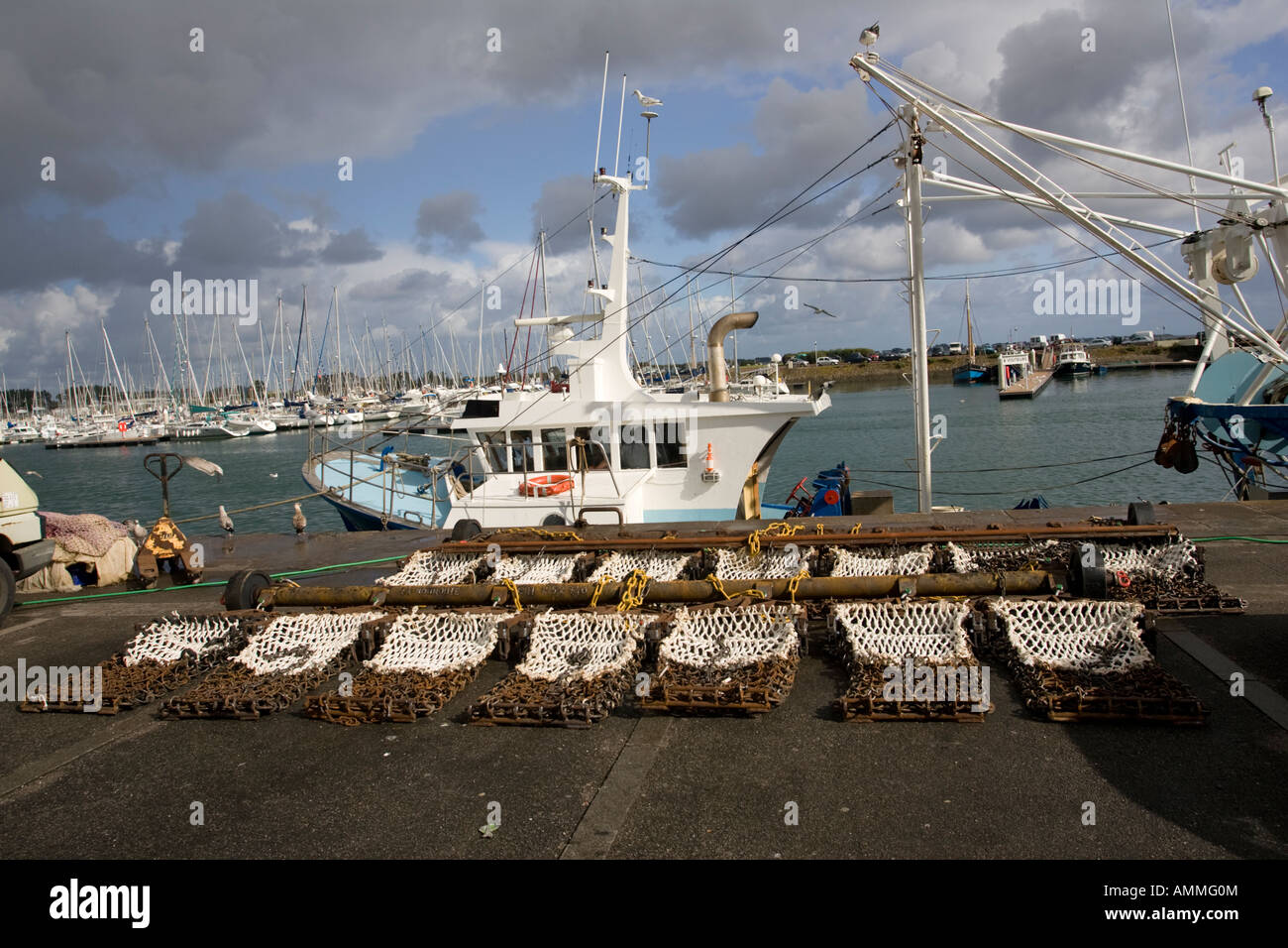 Scallop dredging nets with fishing trawlers Quineville harbour Normandy France Stock Photo