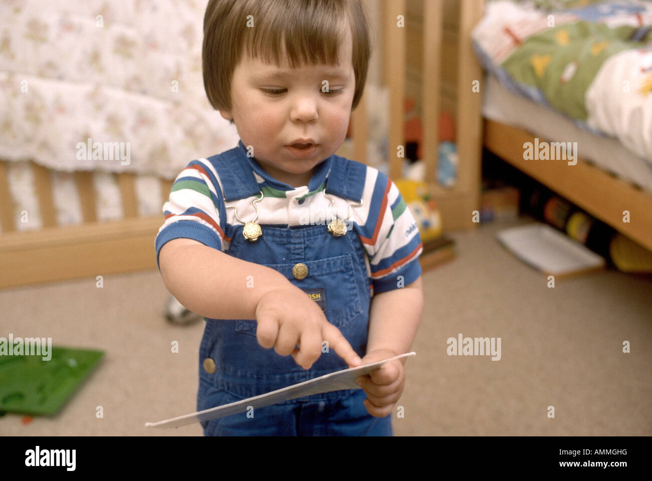 Three year old pointing to a card he holds in his hand Stock Photo