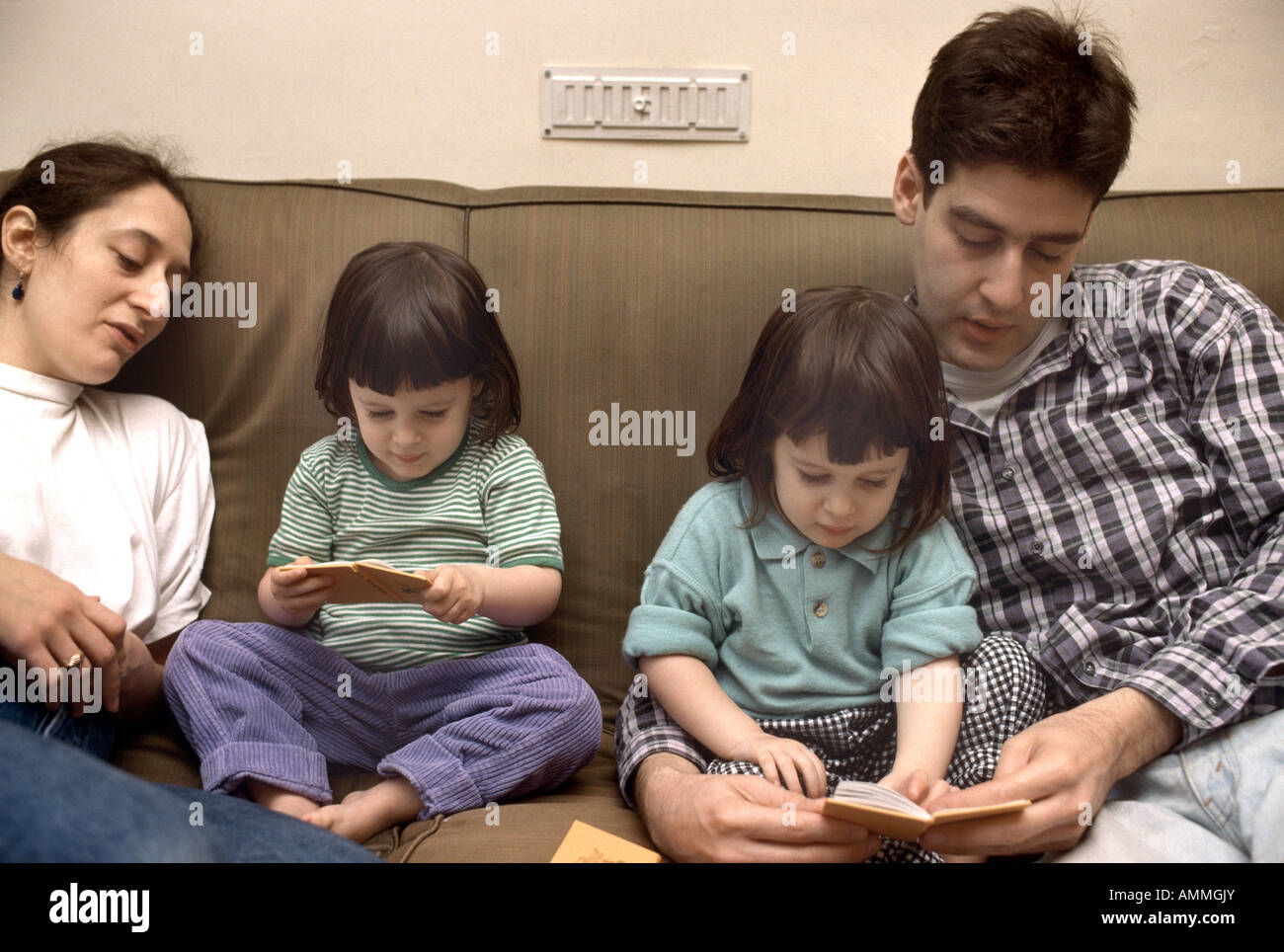 Parents reading books with their twin daughters stock photo alamy
