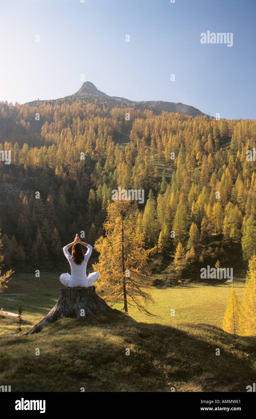 Woman meditating on tree trunk Stock Photo