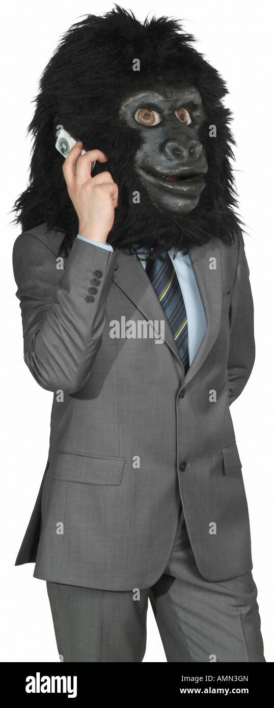 Man in a suit wearing the head of a gorilla costume and making a phone call Stock Photo