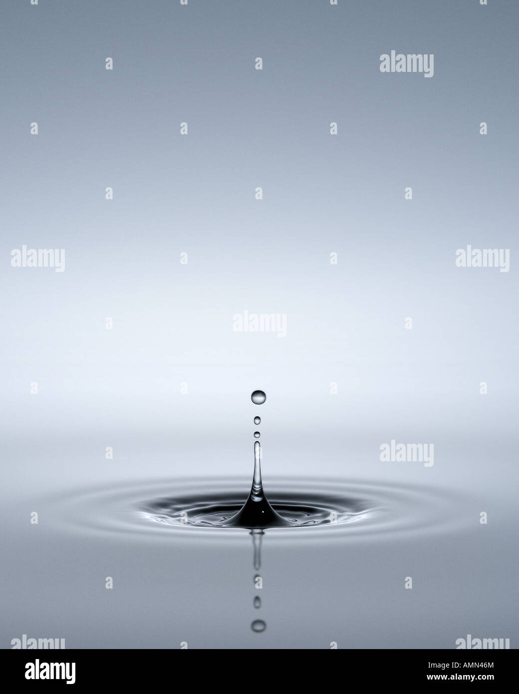 An inverted ripple of water with drops above it Stock Photo - Alamy