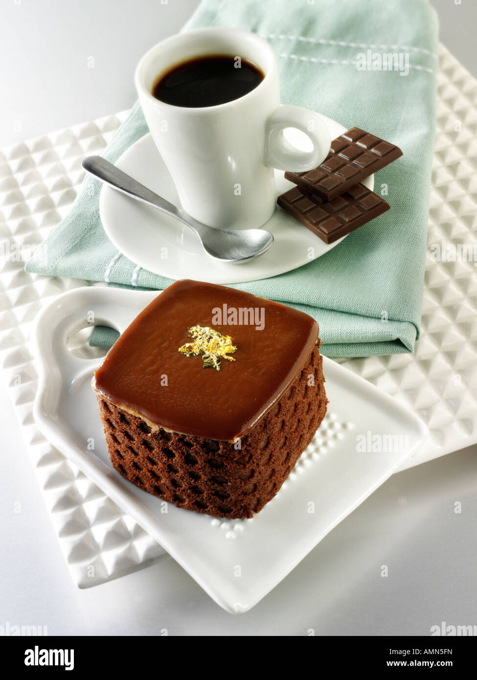 A hand made patisserie speciality rich indulgent chocolate cake filled with with coffee in a white table setting Stock Photo