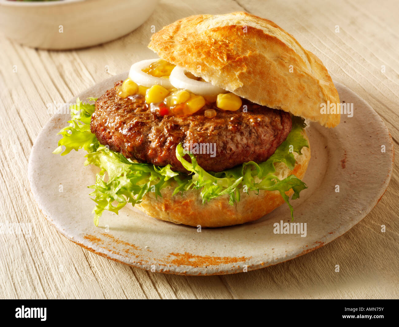 Home made burger in a crusty roll with sweetcorn relish and omion Stock Photo