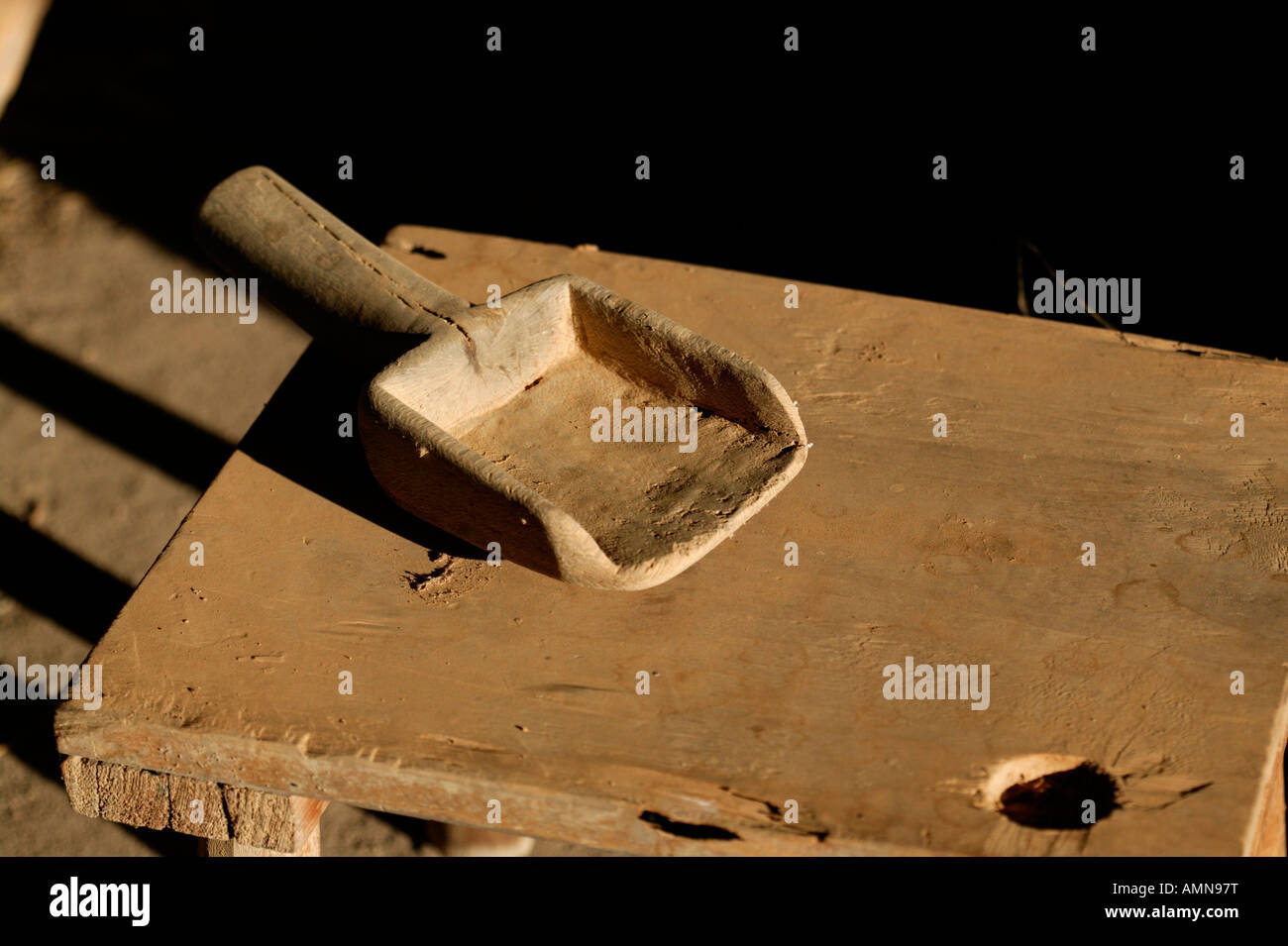An old hand-made, wooden hand trowel used for scooping grain lying on a wooden table Stock Photo