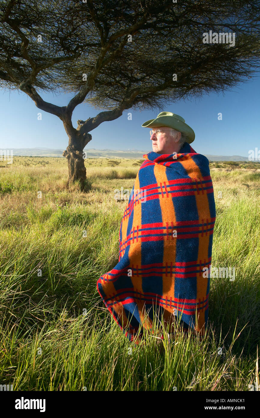 Peter Bender in Senior Elder robe of Masai standing near Acacia Tree in the Lewa Conservancy of Kenya Africa Stock Photo