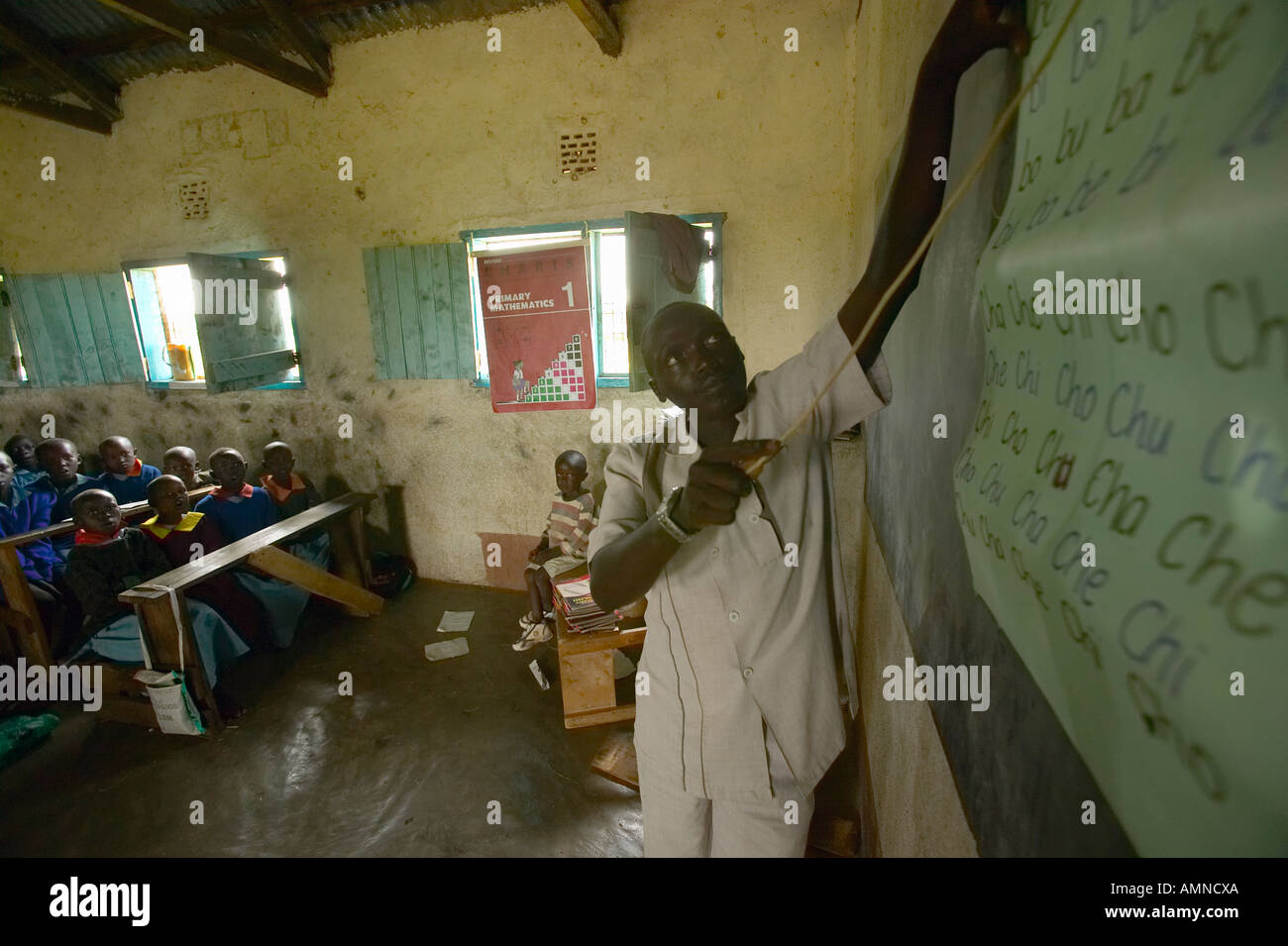 Teacher of English syllables to children in blue uniforms at school behind desk near Tsavo National Park Kenya Africa Stock Photo