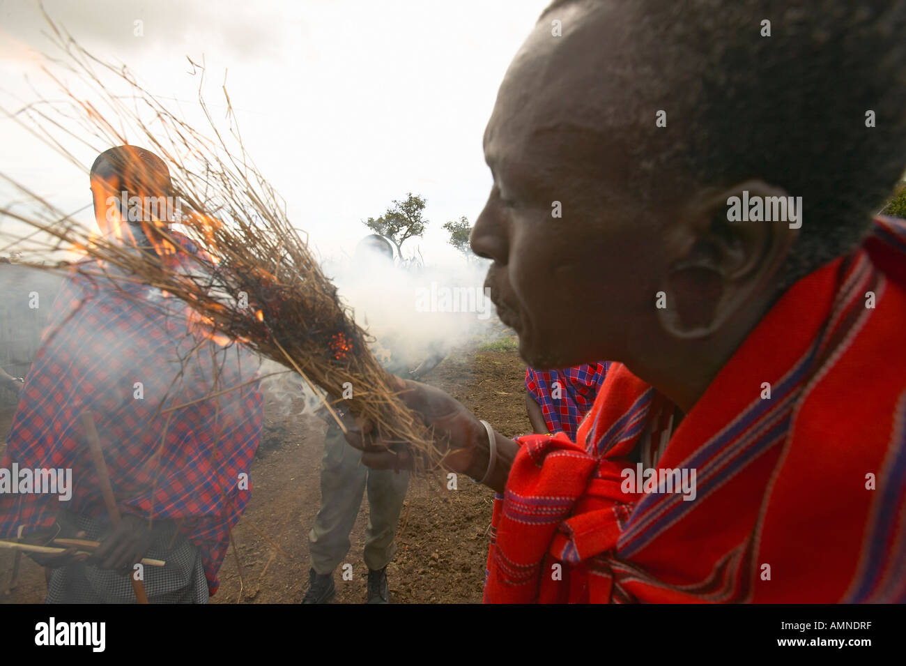 Masai male making fire by rubbing sticks together in village near Tsavo
