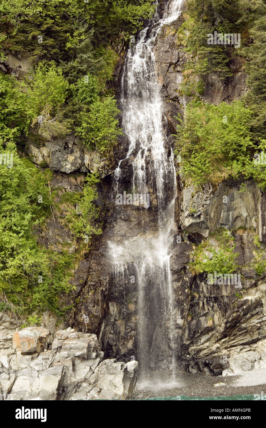 ALASKA SEWARD KENAI FJORDS NATIONAL PARK WATERFALL CASCADING FROM MOUNTAIN SIDE INTO THE OCEAN Stock Photo