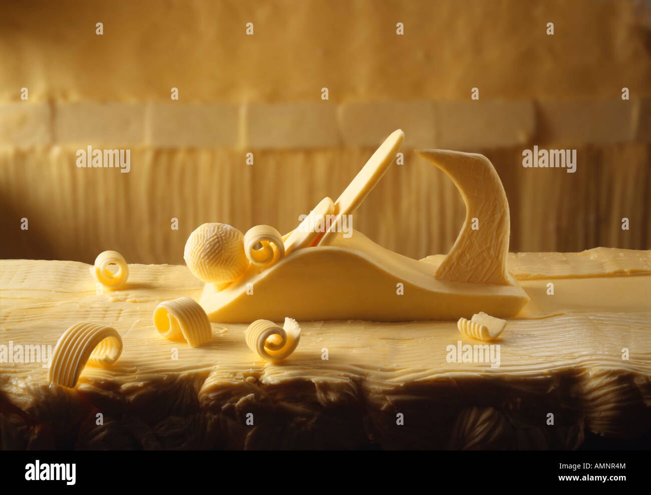 Butter curler. A wood plane made out of butter on work top made out of butter with butter curls. Novelty creative photo. Stock Photo