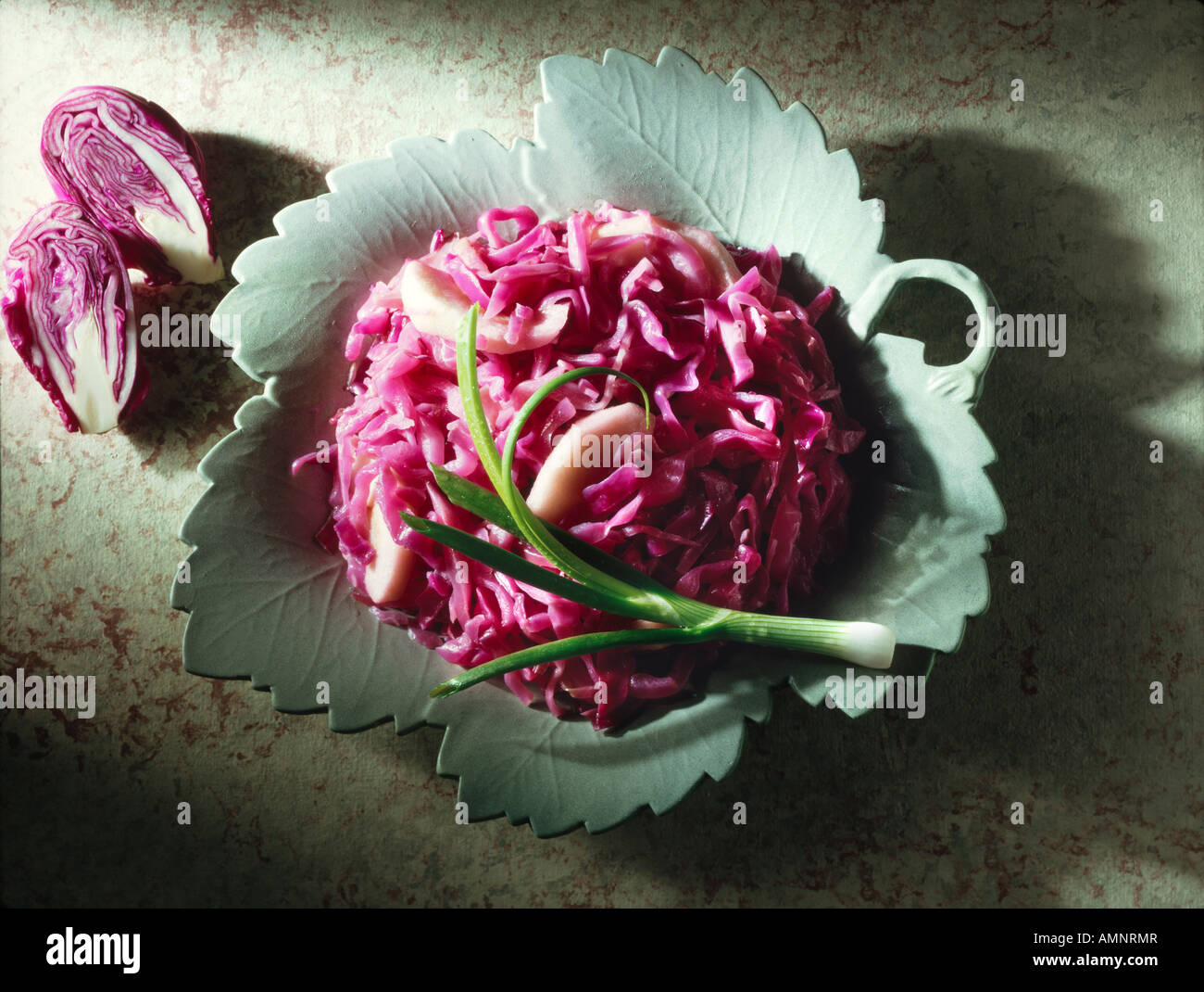 Top shot of shredded red cabbage and apple salad on a grey leaf plate. Stock Photo