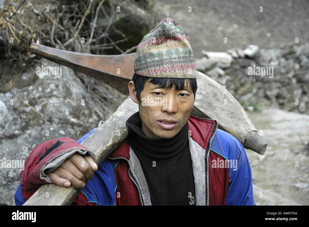 Man wearing a traditional hat carries a plow Karte Annapurna Region Nepal Stock Photo