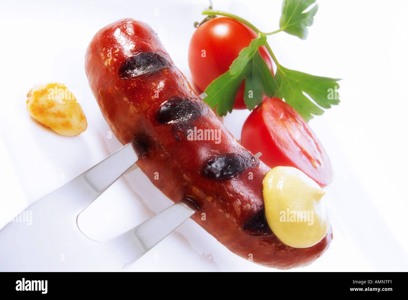 Roast sausage with mustard on fork Stock Photo