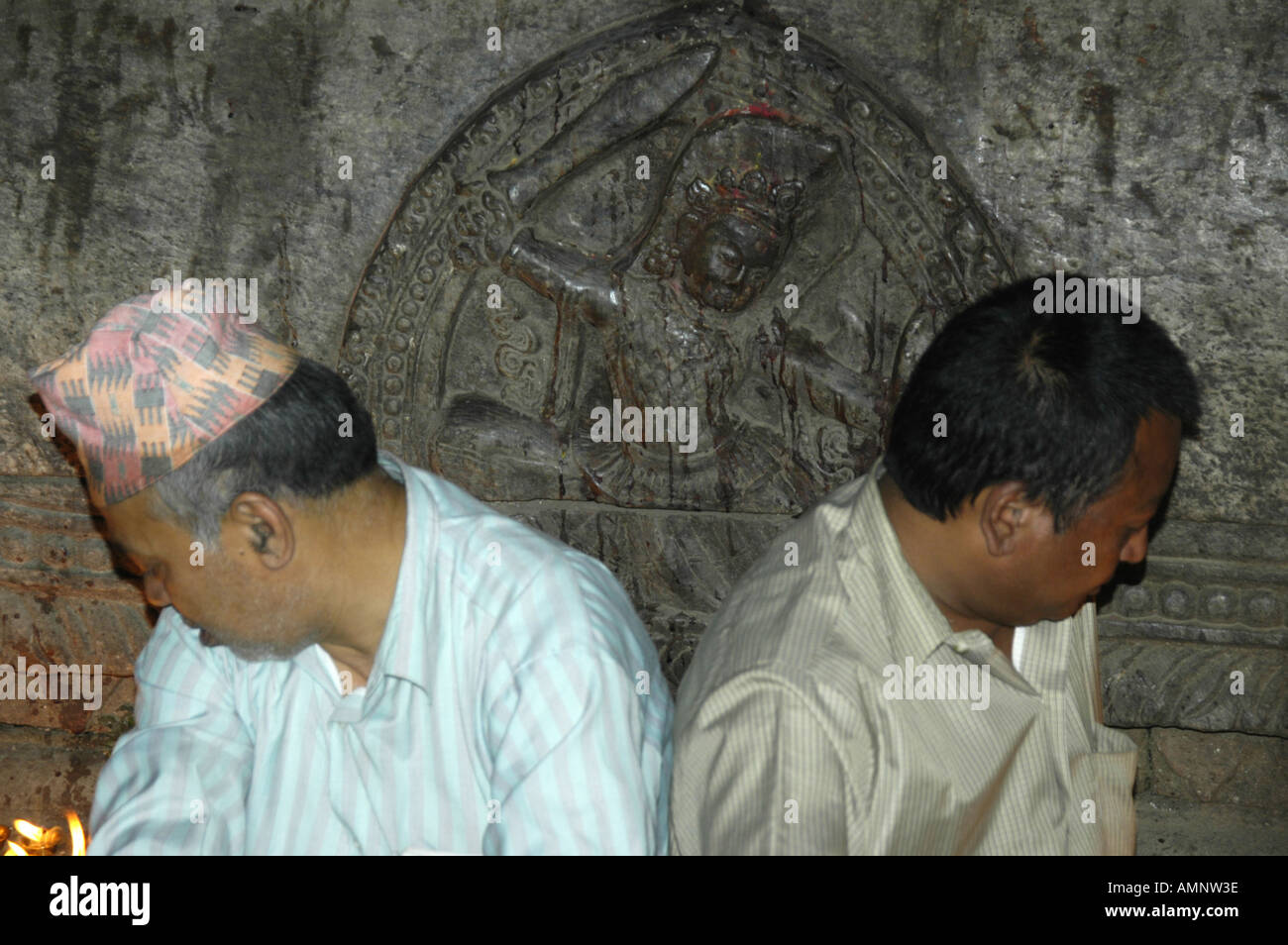 Two men look to left and right with a relief of a god with a sword Kathmandu Nepal Stock Photo