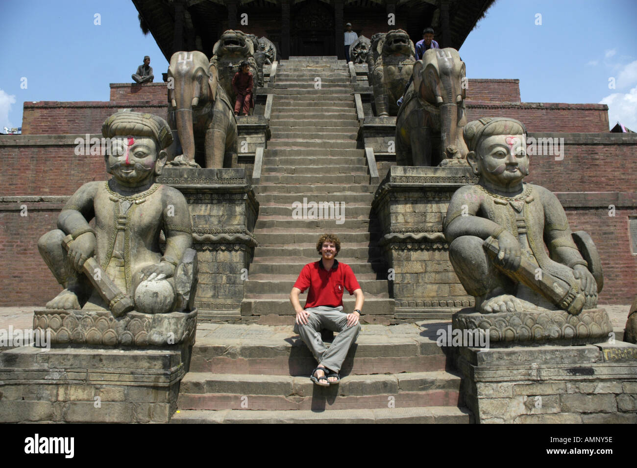 MR Tourist is sitting on the steps of Fasidega Temple between huge stone figures Durbar Square Bhaktapur Nepal Stock Photo