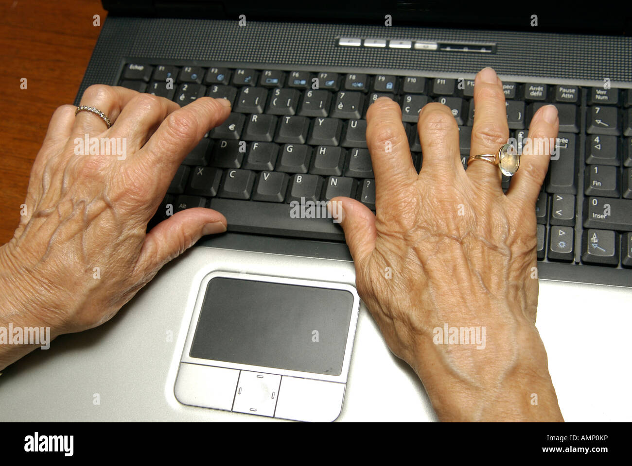 Old hands of woman typing on a keyboard of a laptop computer. Stock Photo