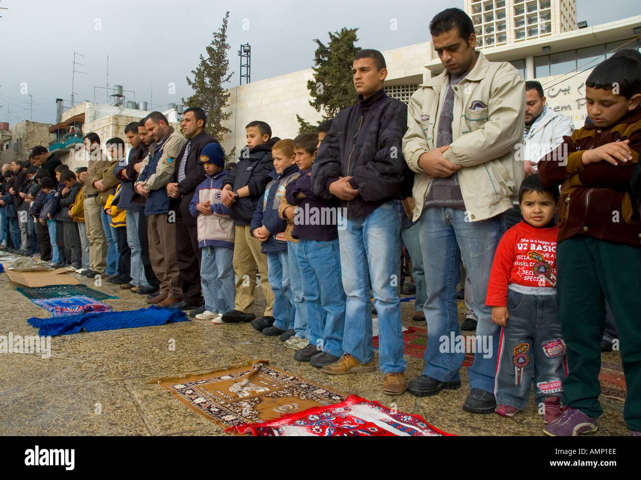 Palestinian Authority Bethlehem Manger Square row of muslem men praying outside with young child  Stock Photo