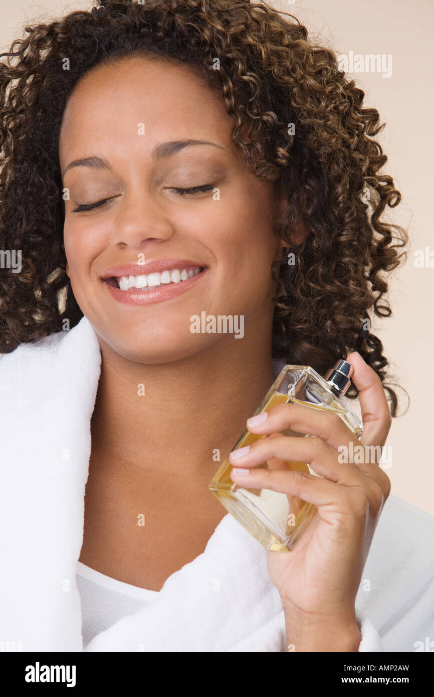 African woman putting on perfume Stock Photo