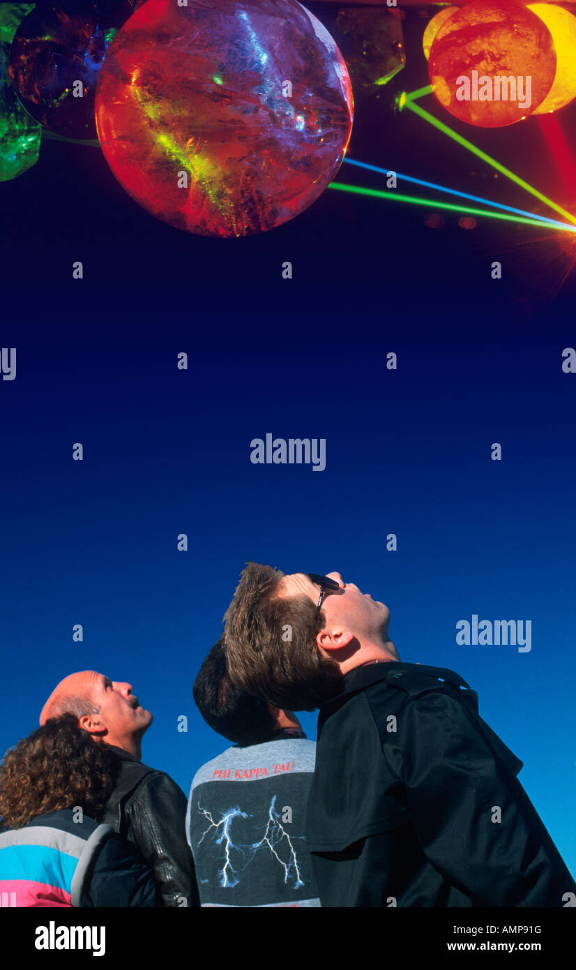 Composite image of spectators looking up at planets and stars in the dark blue sky Stock Photo