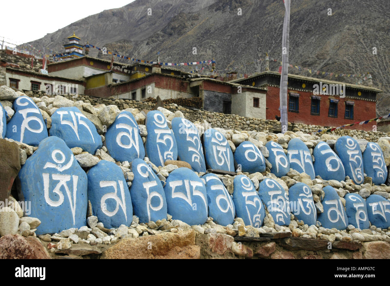 Tibetan script on blue painted rocks in a row in front of old monastery Tashi Gompa Phu Nar Phu Annapurna Region Nepal Stock Photo