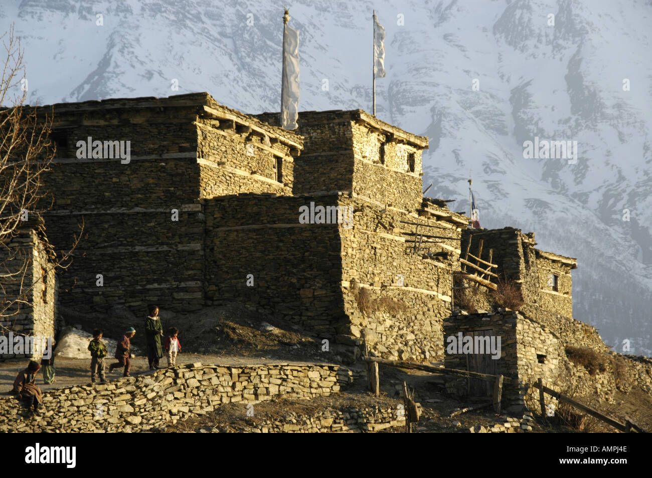 Children seem small next to stone houses in the evening light Ngawal Annapurna Region Nepal Stock Photo