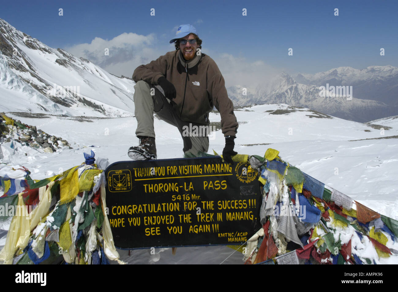 MR successful mountaineer at the sign with prayer flags in the snow Thorung La Pass 5416 m Annapurna Region Nepal Stock Photo
