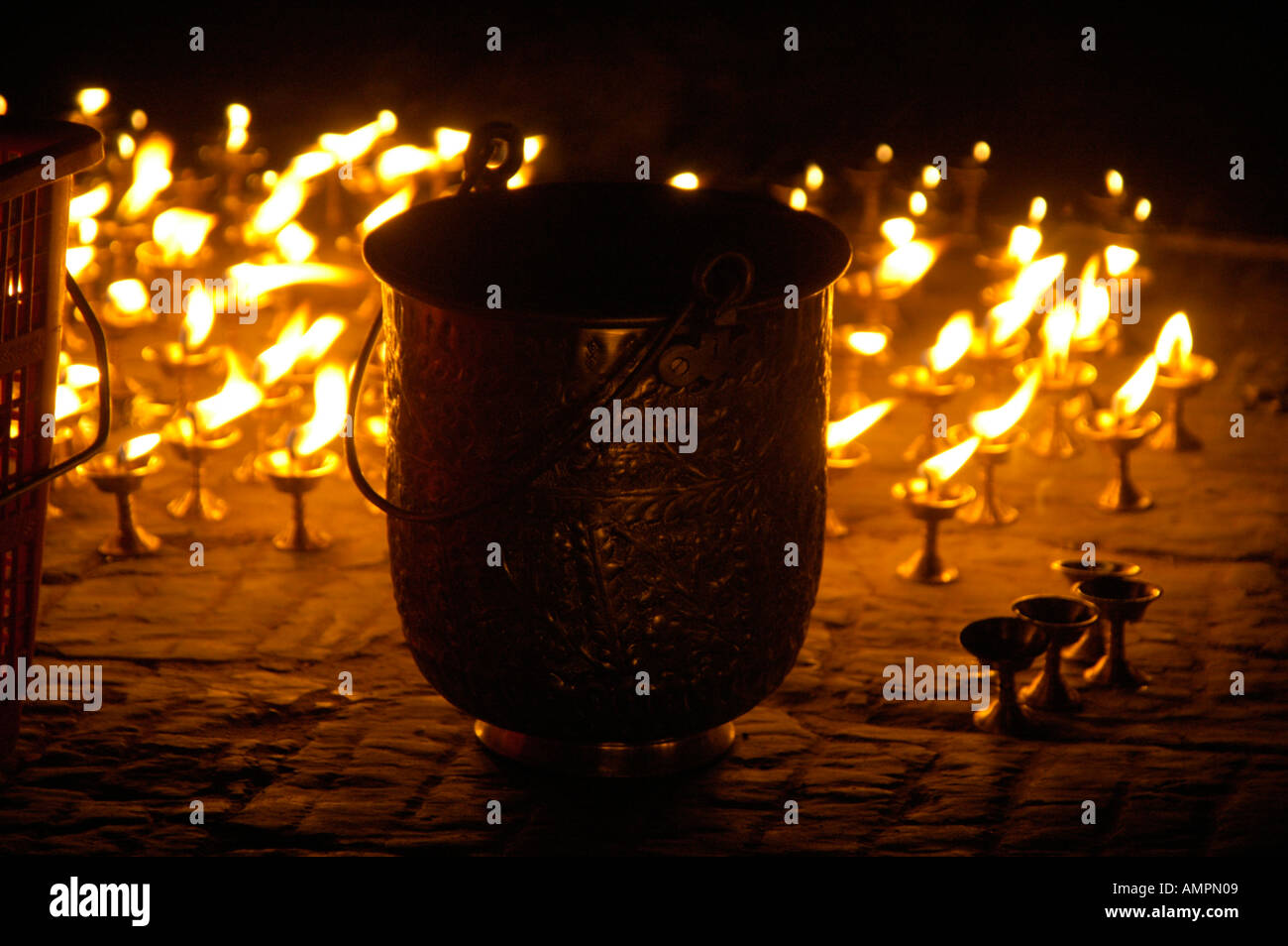 Butter lamps are burning on the ground behind a metal pot at a festival Kathmandu Nepal Stock Photo