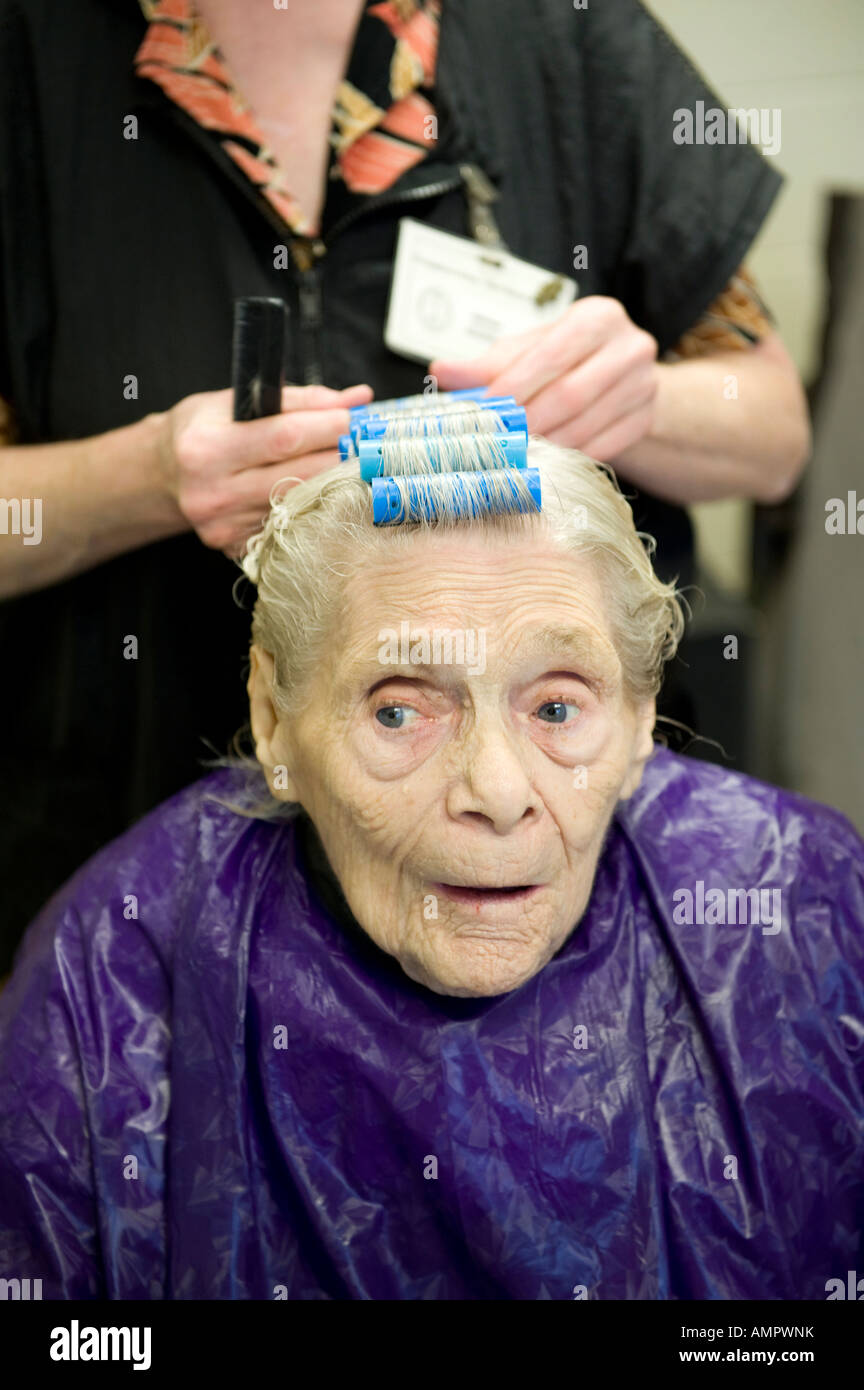Elderly senior female having hair done by hairdresser in a nursing home