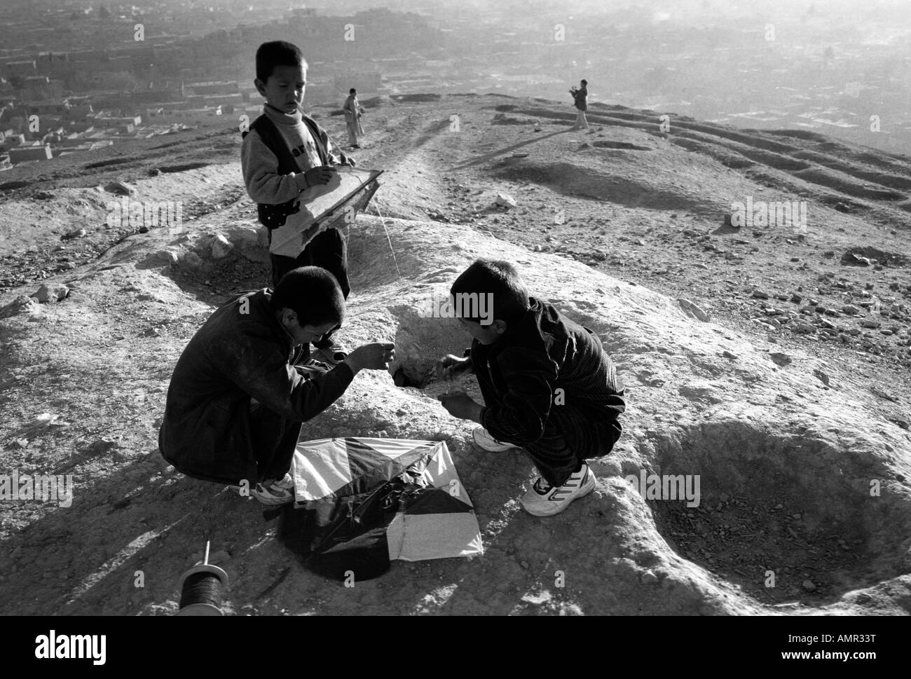 Boys repair their kite on a hill in Kabul Afghanistan August 2005 Stock Photo
