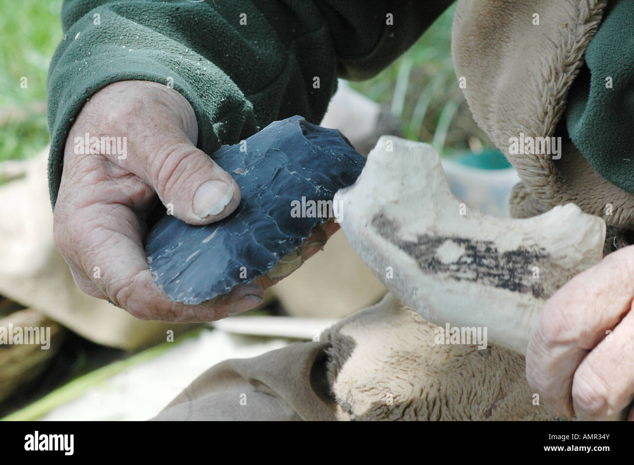 Flint knapper at work on a tool with an antler as the hammer. Stock Photo