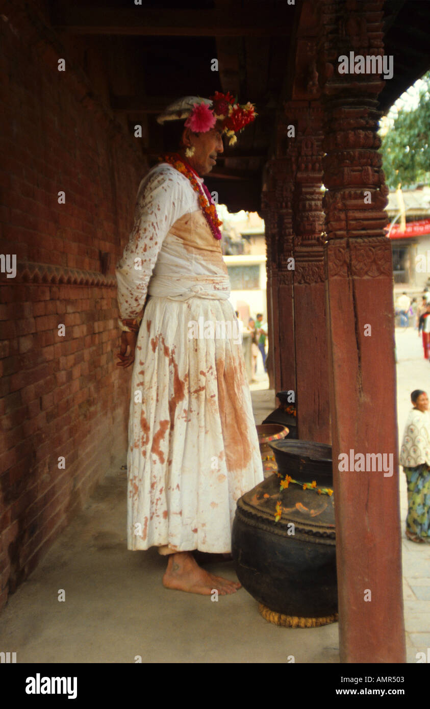 Nepal shaman priest on steps of temple after having made animal