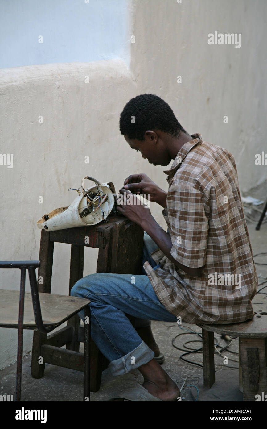 A young African man repairing a sewing machine on the streets of Stone Town Zanzibar Tanzania Africa Stock Photo