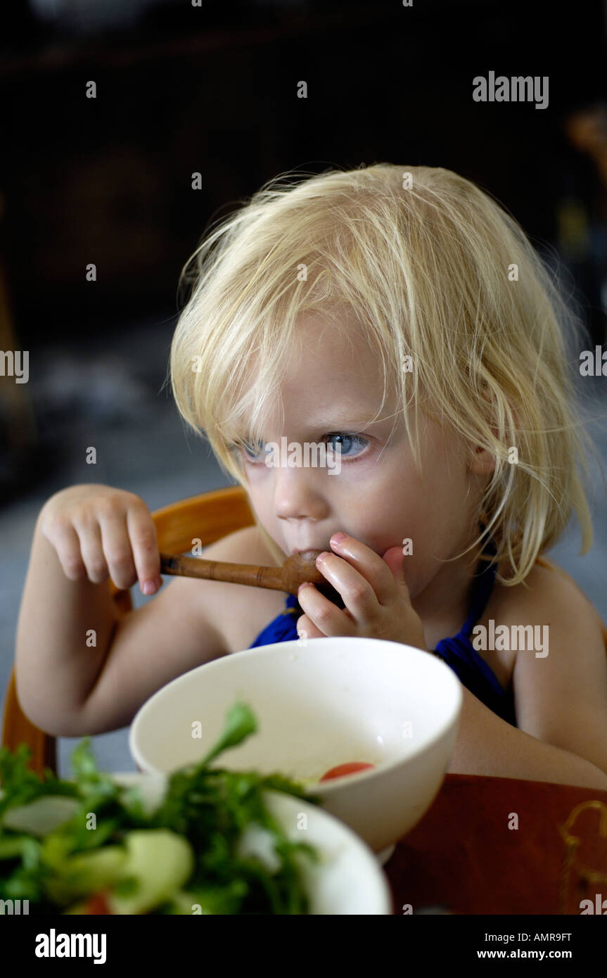Baby girl feeding herself in a high chair using a spoon. 2007 Stock Photo