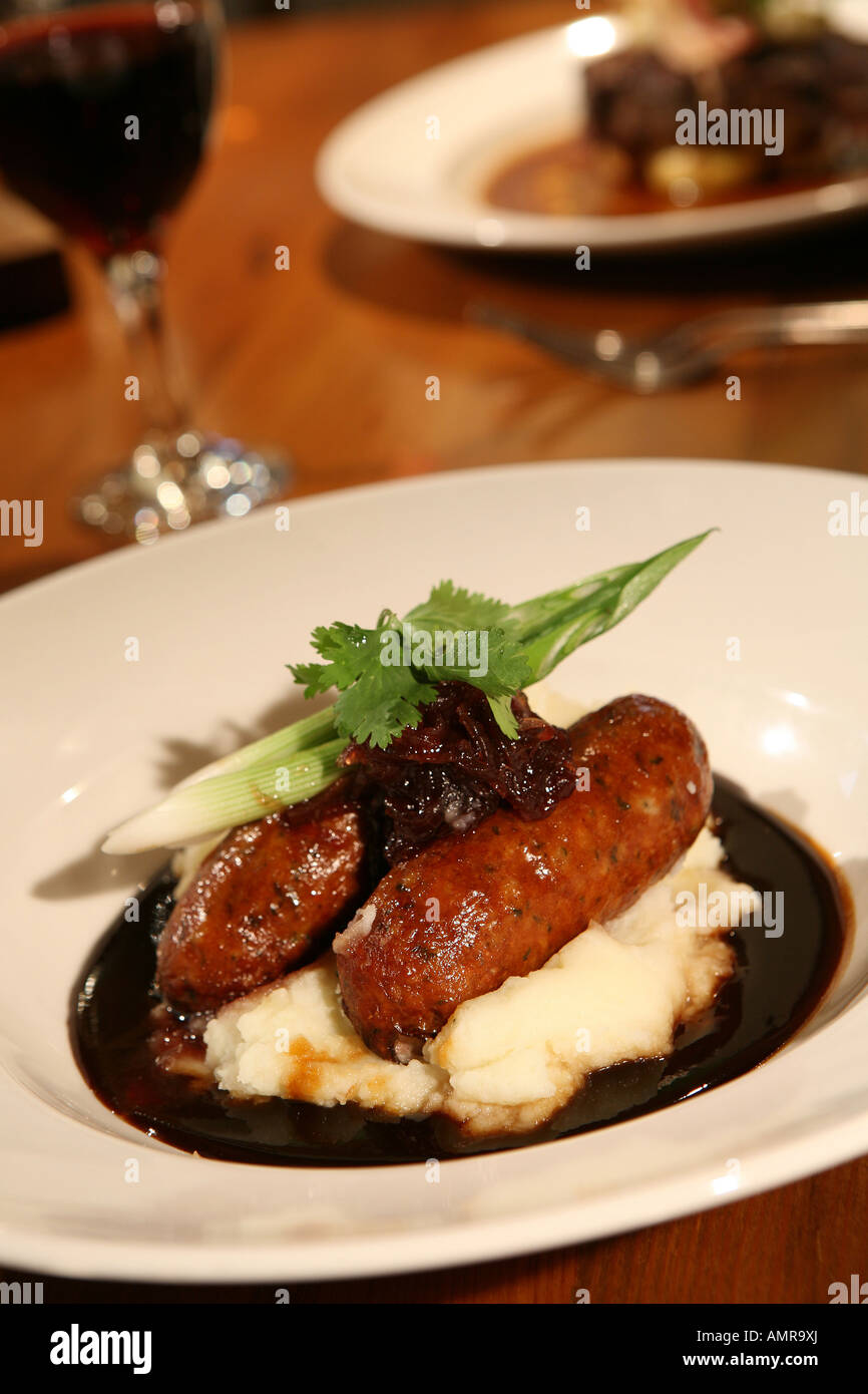 Sausage and mash with gravy and green dressing on restaurant table Stock Photo