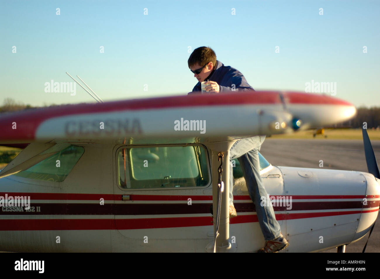 A pilot performs a pre-flight check on a Cessna 152 2 person airplane Stock Photo