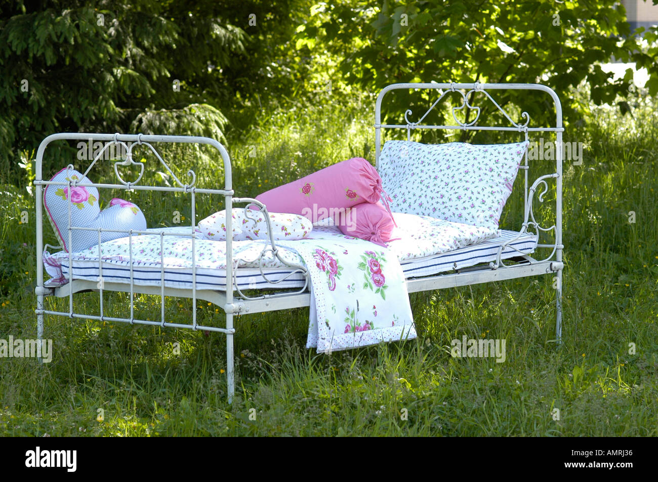 Bett schmiedeisernes Bett im Grünen Ambiente Wohnaccesoires bed in a green meadow Stock Photo