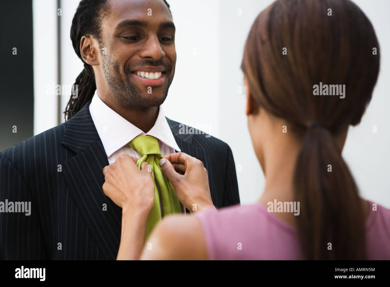 African woman adjusting husband’s necktie Stock Photo