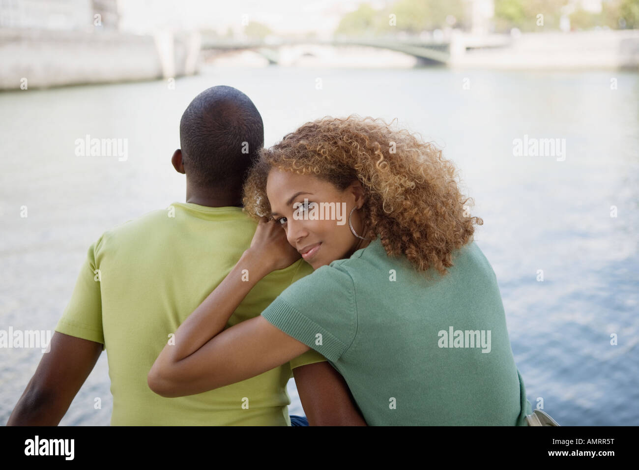 African couple sitting next to water Stock Photo