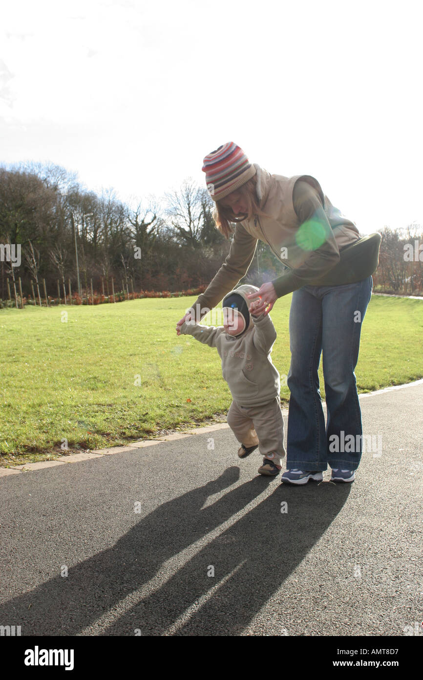 A one year old baby toddler learning how to walk with the help of his
