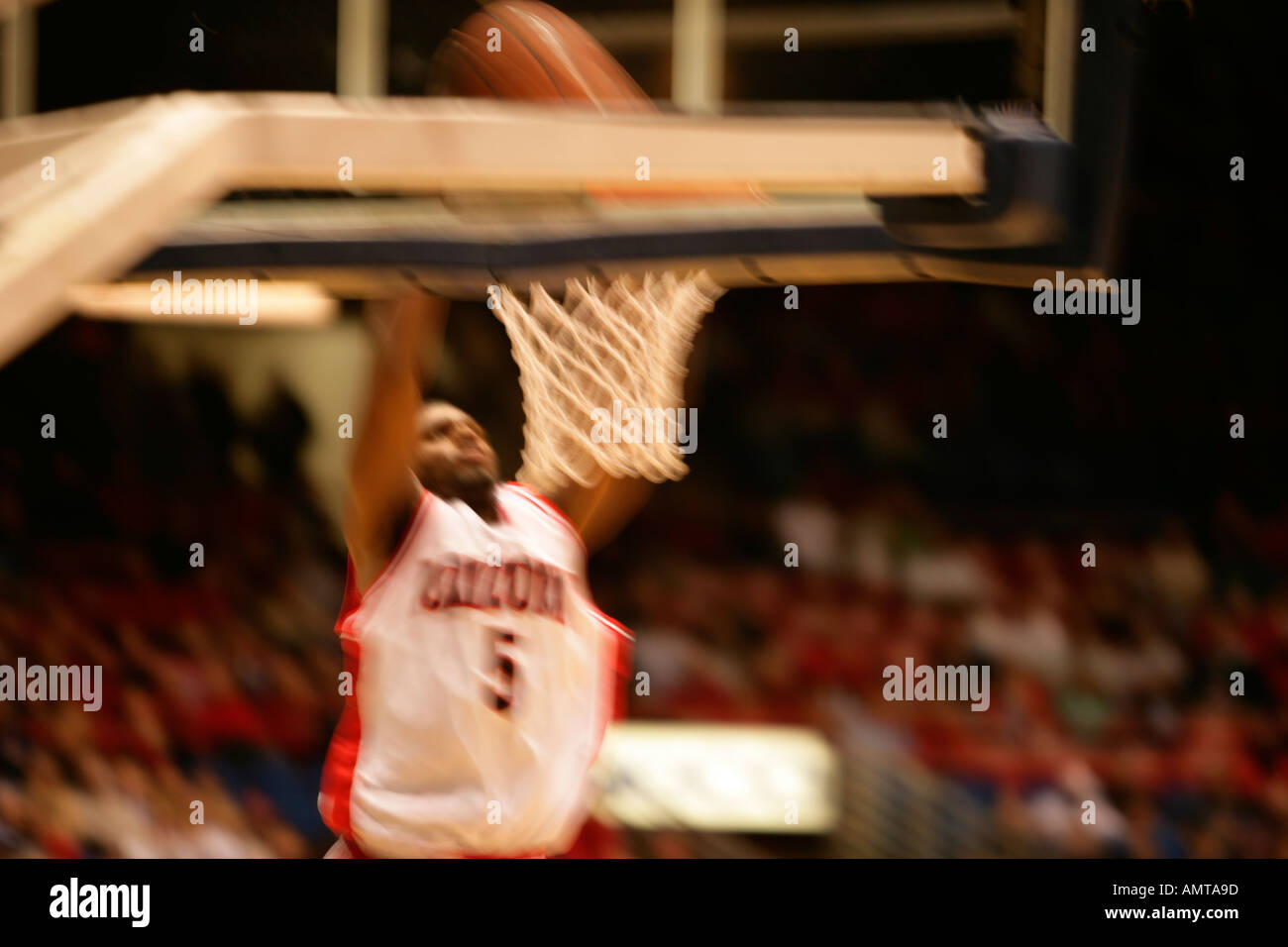 A slow shutter speed shot of a basketball player making a shot in this case a slam dunk Stock