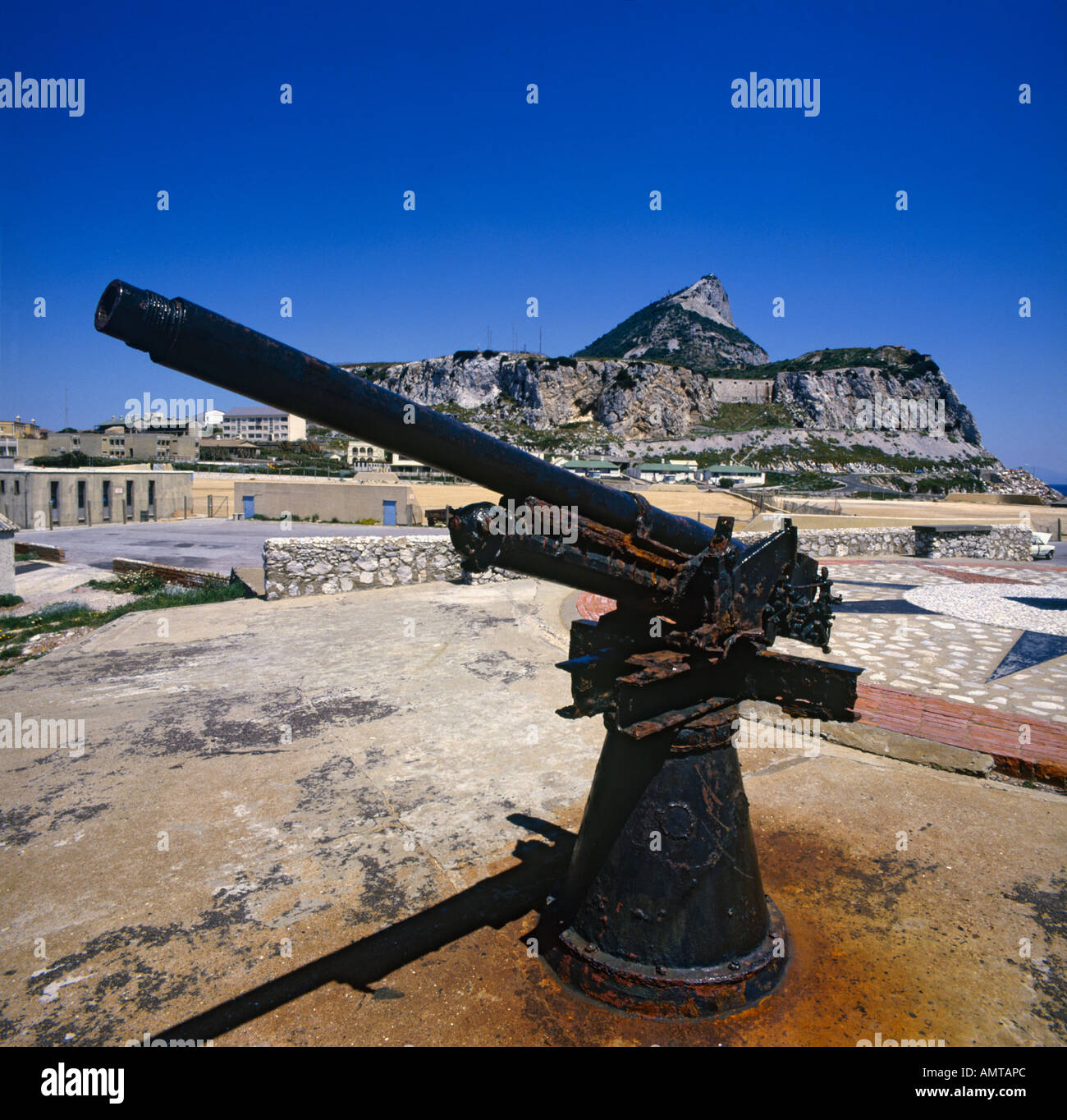 An old rusting artillery gun memorial on stony plinth with Military buildings at base of Europa Point on Gibraltar Stock Photo