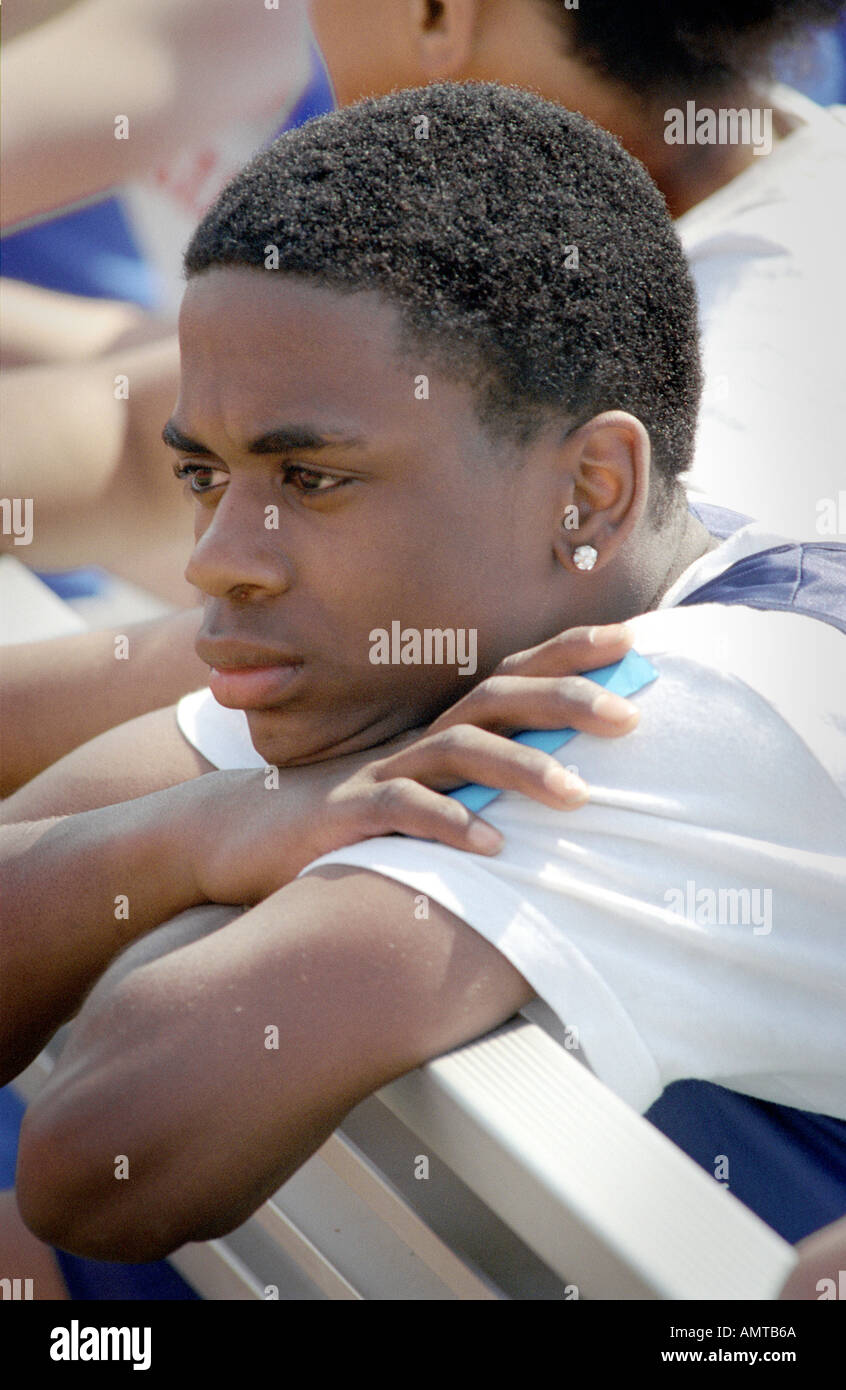 Black 14 year old male youth with earring stares in a pensive setting Stock Photo