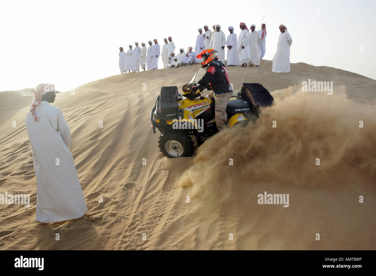 Group of Arab men in the desert watching a quad rider Stock Photo