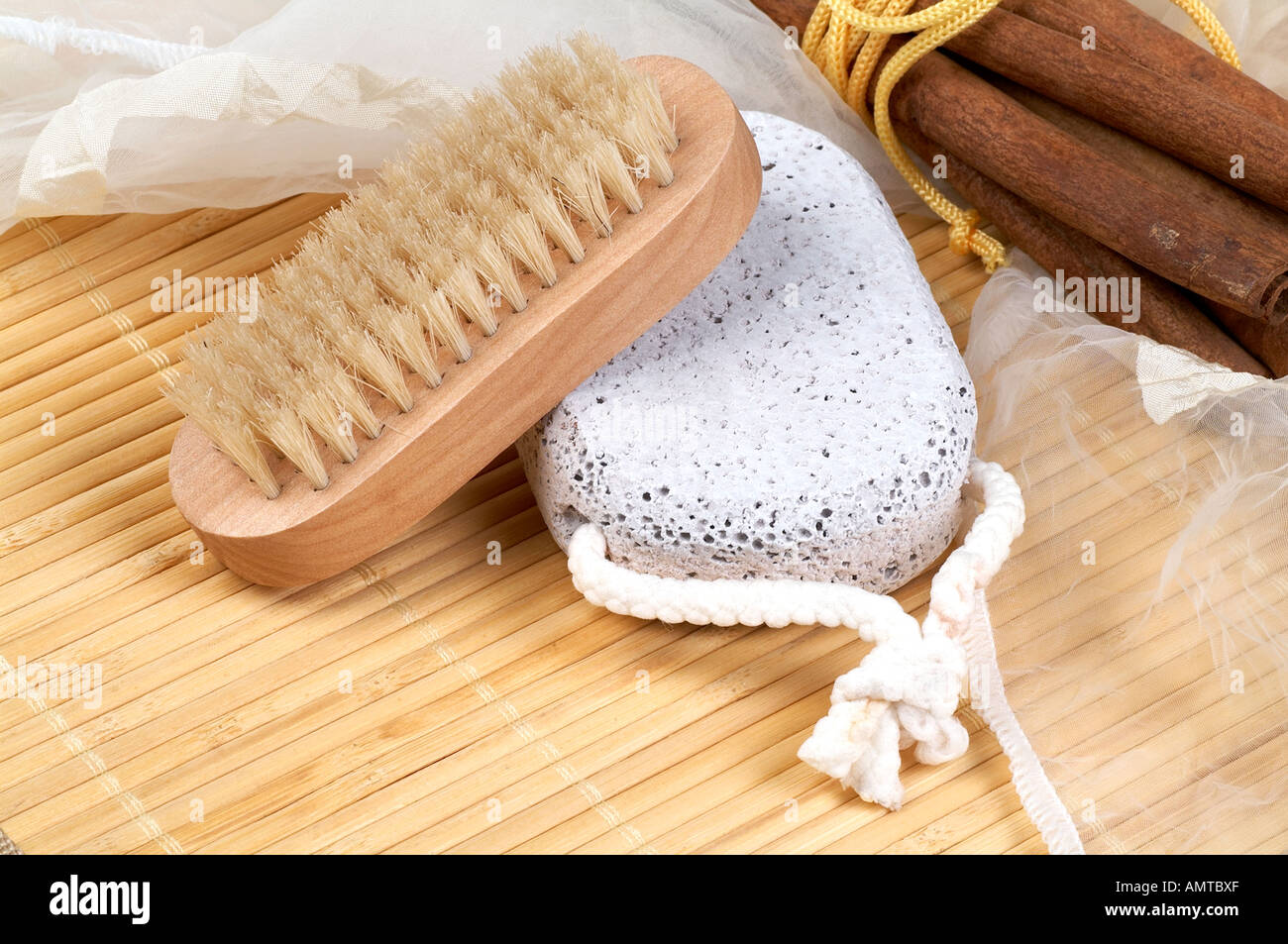 Nail brush, pumice stone and cinnamon sticks on bamboo surface Stock